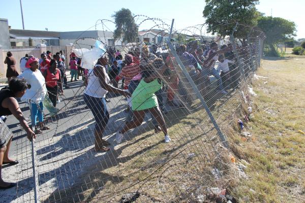 Angry parents taking down the school fence. Photo by Mihle Pike.