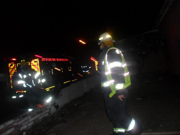 Firemen extinguish the fire of the drug house. Photo by Tariro Washinyira.