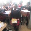 A learner sits without a desk in a crowded classroom. Photo by Mary-Anne Gontsana.
