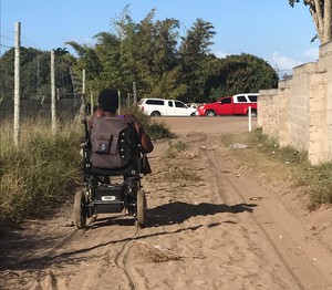 Photo of a person in a wheelchair on a dirt road