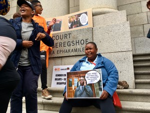 Photo of woman with poster outside court