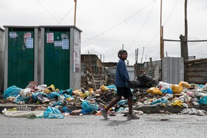 A youth walks pass rubbish in Sheffield road in Philippi East