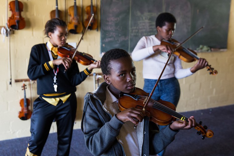 Photo of students learning violin at an outreach program in Masiphumelele
