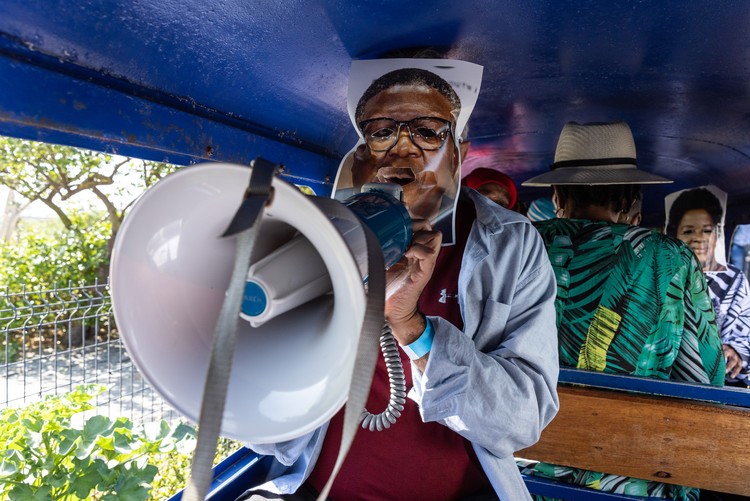 Zackie Achmat, wearing a photo of Fikile Mbalula on his face, addresses the protesters. Behind the fun was a serious message about the collapse of commuter rail across South Africa.