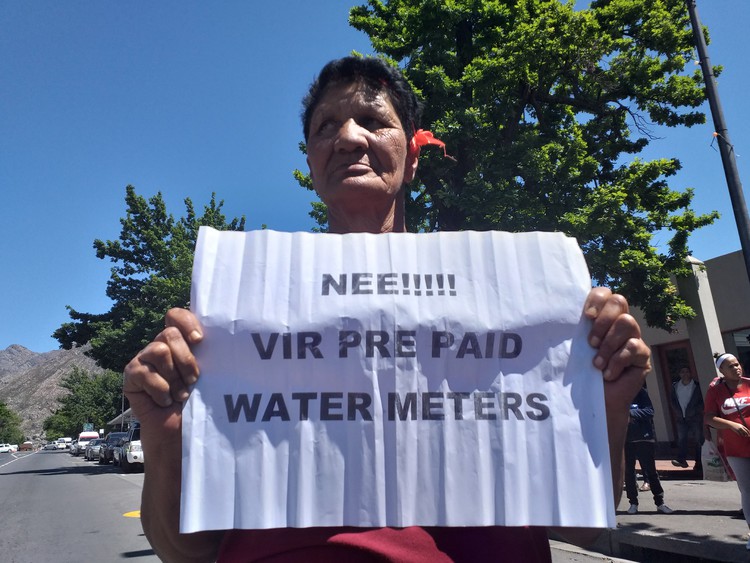 Photo of woman holding placard complaining about water meter