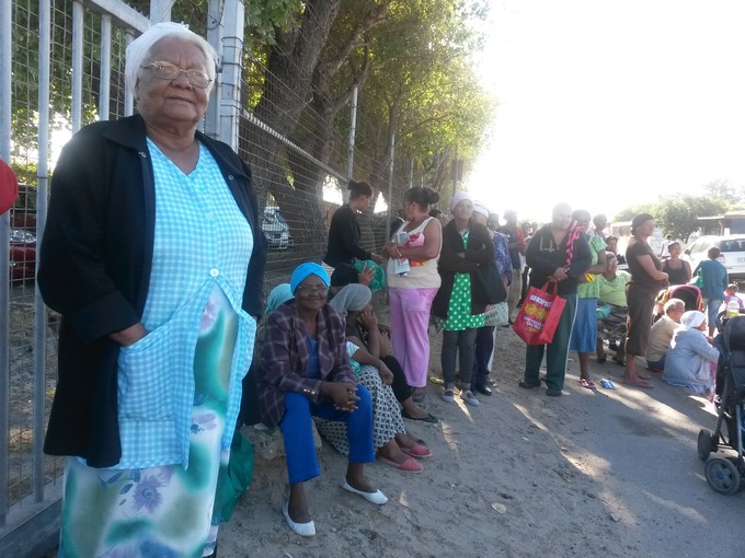 Photo of a woman standing in a queue for a food parcel