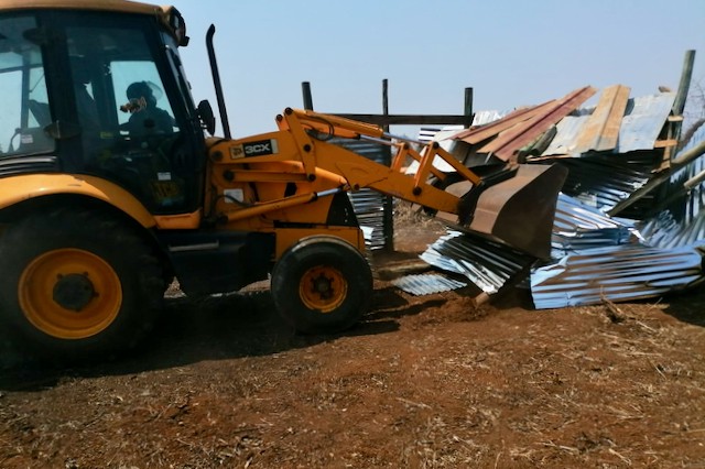 Photo of a bulldozer flattening a shack