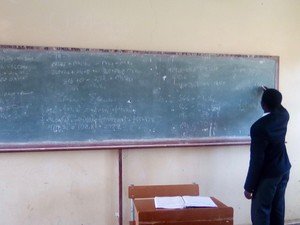 Photo of a school learner writing on a blackboard