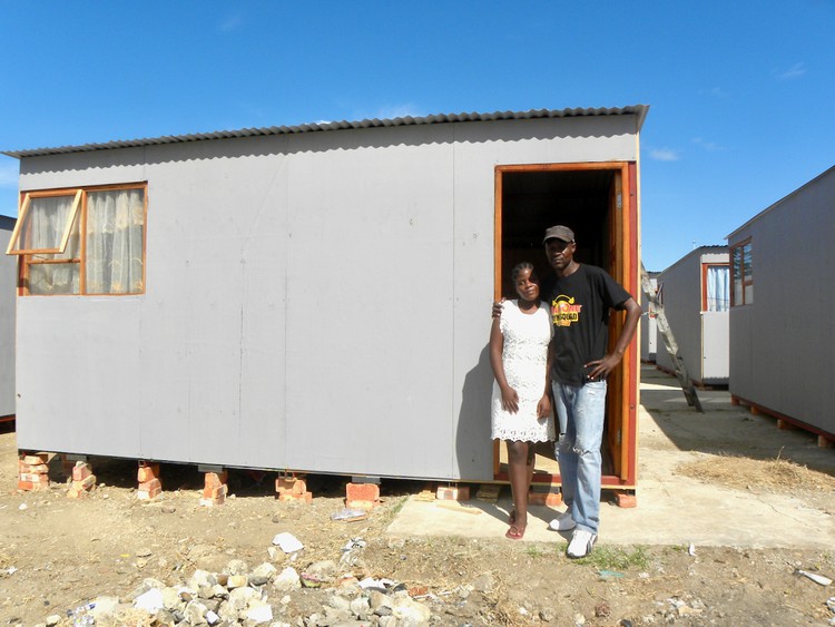 Photo of two people in front of a temporary house