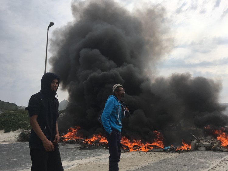 Photo of men standing in front of burning barricade