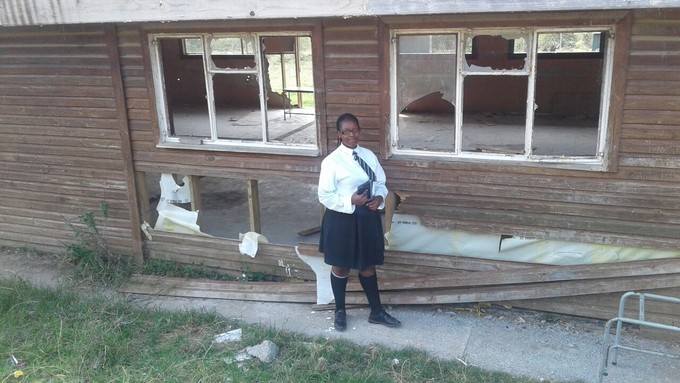 Photo of student outside dilapidated school