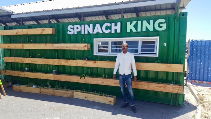 Photo of a man infront of a shipping container made into a shop
