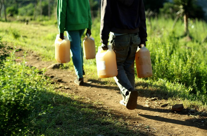 The boys carry the water uphill. Notice the brownish-orange colour of the water.
