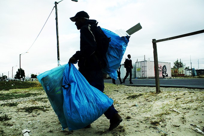 Photo of Plaatjies carrying bags of scrap in the evening.
