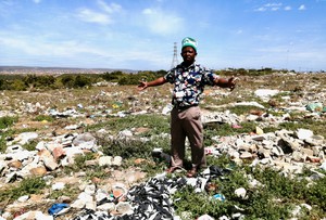 Photo of a man standing in a field of rubbish