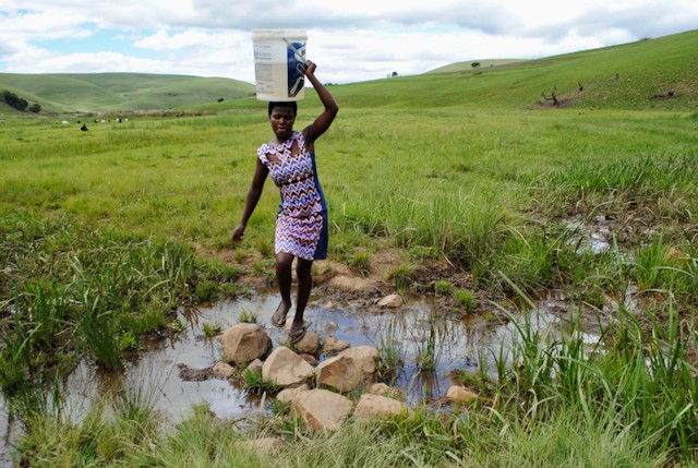 Photo of a woman with a bucket on her head