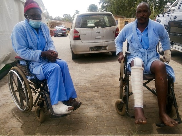 Photo of two people in wheelchairs in a parking lot