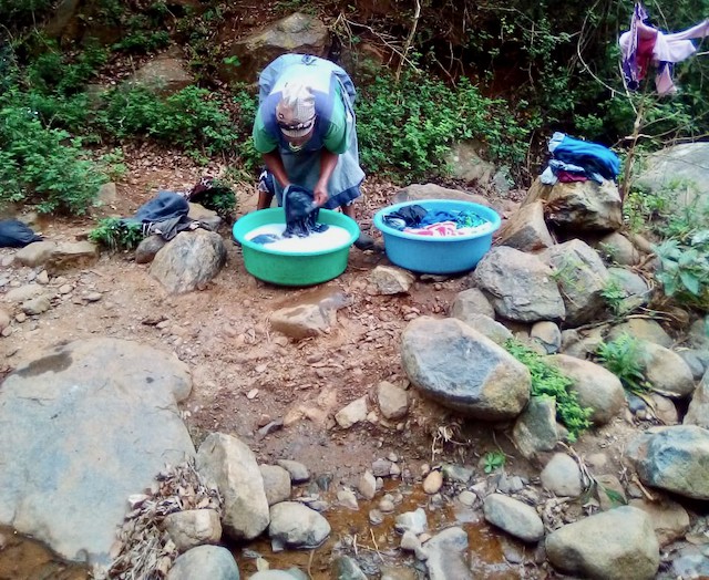 Photo of a woman washing clothes at a river