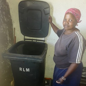 Photo of a woman holding up the lid of a black bin