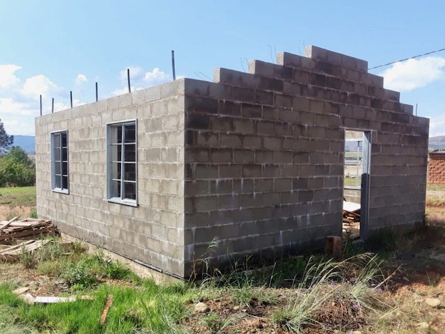 Photo of a house under construction with bare walls and no roof