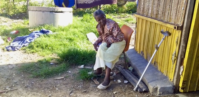 Photo of a woman in front of her shack