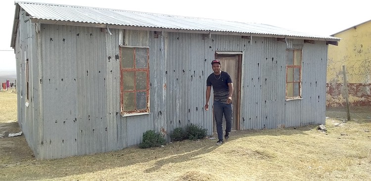 Photo of a shack and a man in front
