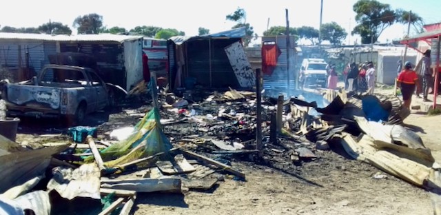 Photo of a burnt shack and bakkie