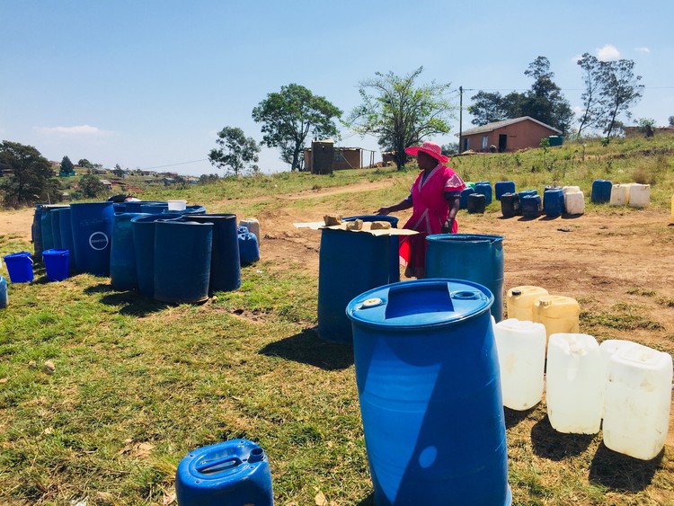 Photo of woman waiting with water containers