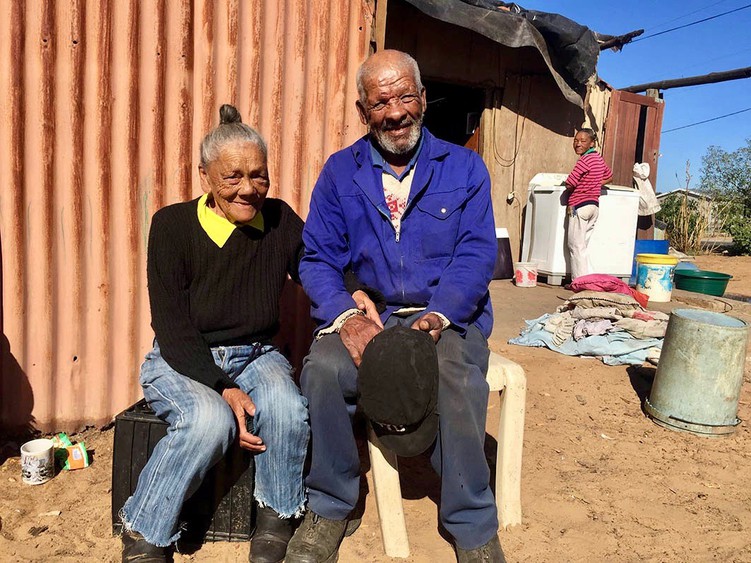 Photo of two old people in front of a shack