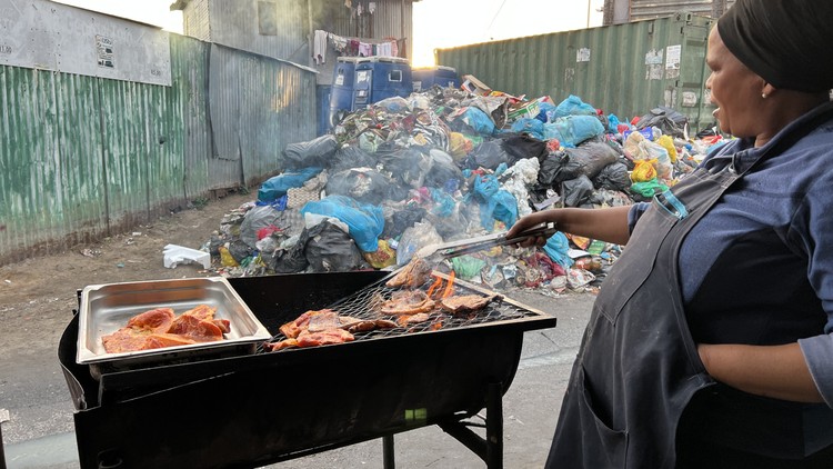 Street vendor Emihle Phoswa braais pork chops and chicken wings near garbage in Dunoon. - Peter Luhanga
