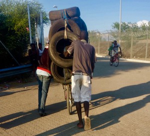Photo of young men pushing a bicycle loaded with car tyres