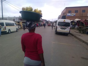 Photo of woman with bucket of oranges on her head