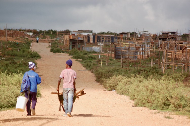 Photo of two people in front of many shacks