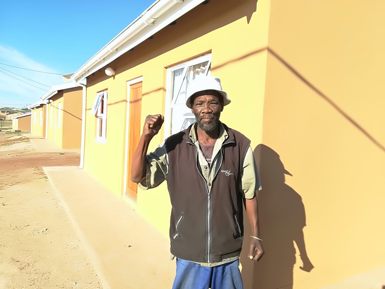 Photo of man with raised fist in front of house