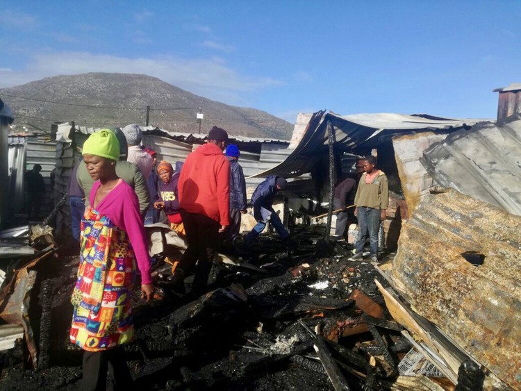 Photo of burnt shacks and a woman