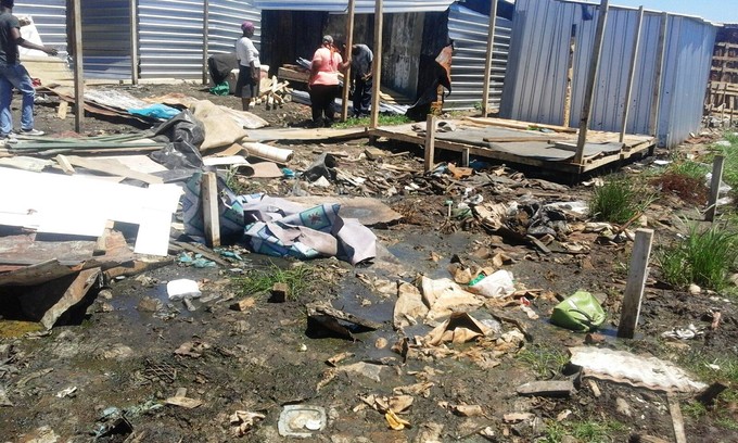 Photo of demolished shacks in mud