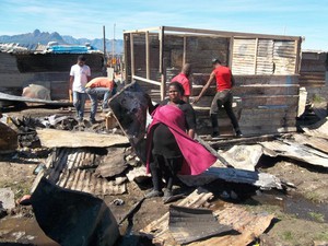Photo of a woman with fire debris and shacks being built