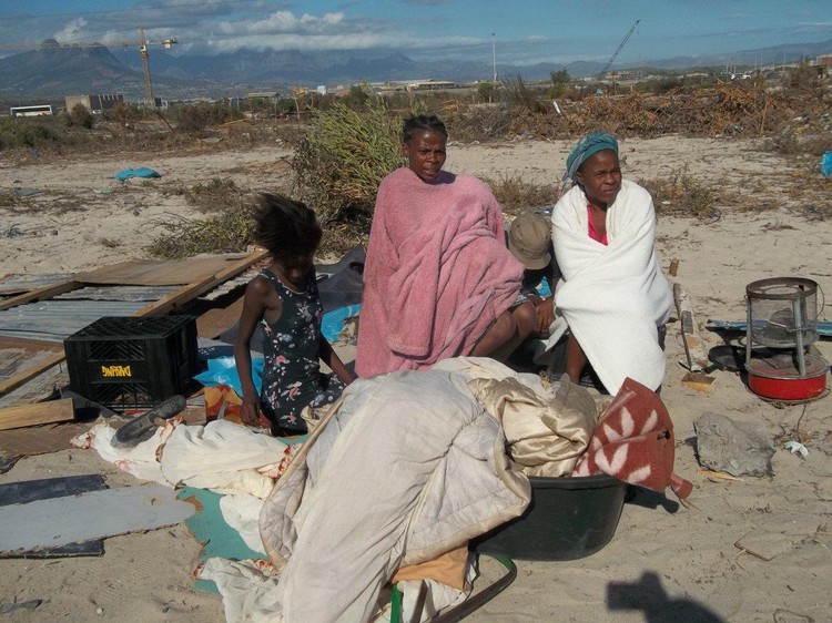 Photo of women sitting with their belongings on the ground after an eviction