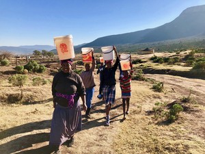 Photo of people walking with buckets on their heads