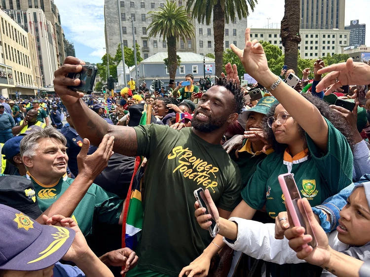 Springbok rugby captain Siya Kolisi takes a selfie with a fan during the Springboks rugby team tour in Cape Town. They came out to celebrate their 2023 Rugby World Cup victory. - Matthew Hirsch