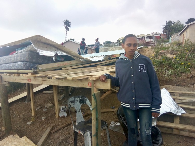 Photo of a person in front of a demolished shack